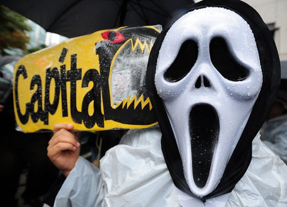 Un manifestante de Corea del Sur con una máscara sostiene una pancarta durante la manifestación Ocupar Seúl como parte de las protestas en todo el mundo
